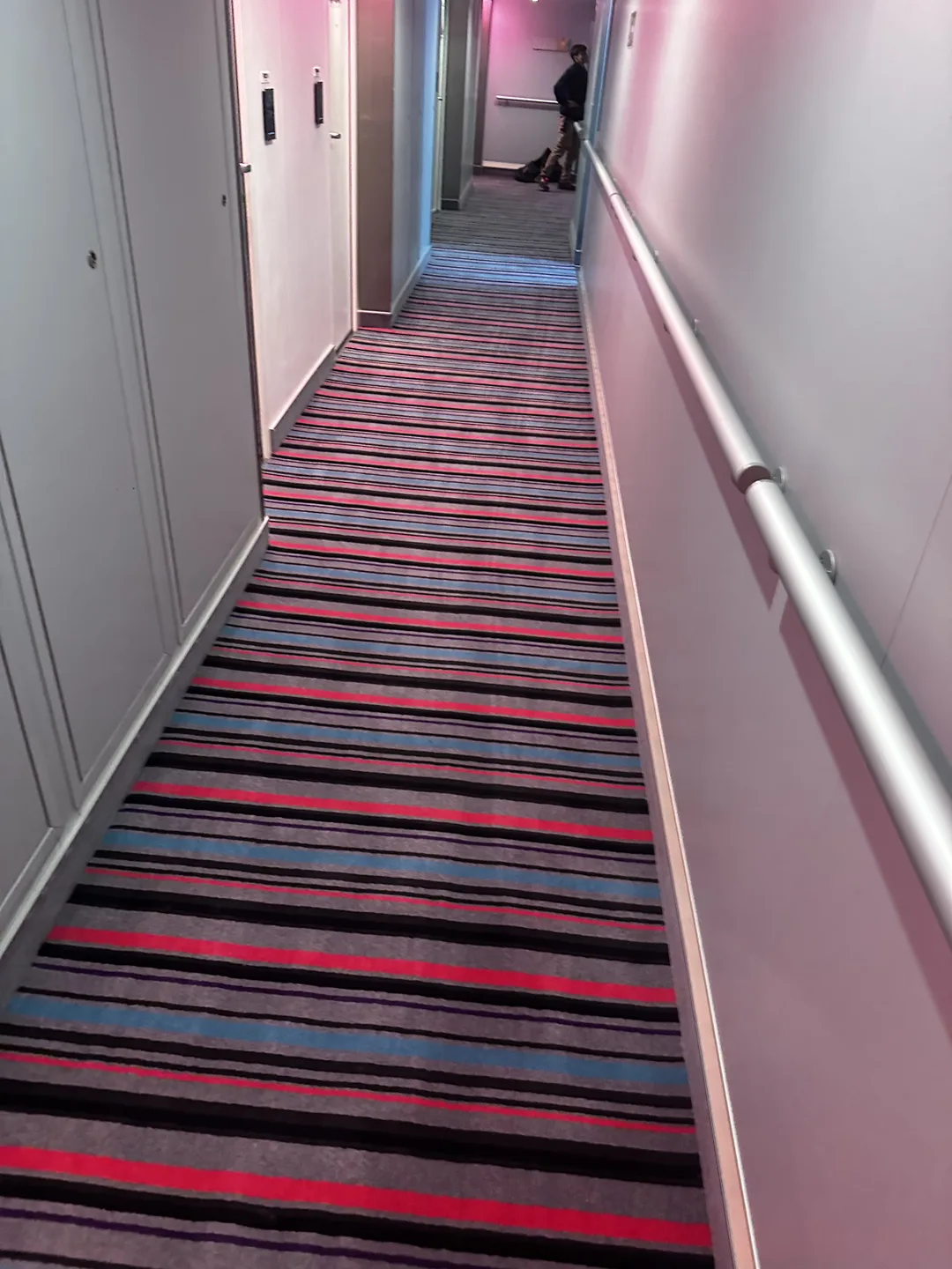 Striped carpet running the length of a corridor beside a handrail