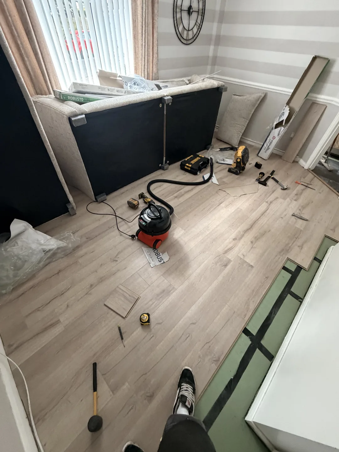 Wood-effect floor being fitted in a room with tools and packs of boards