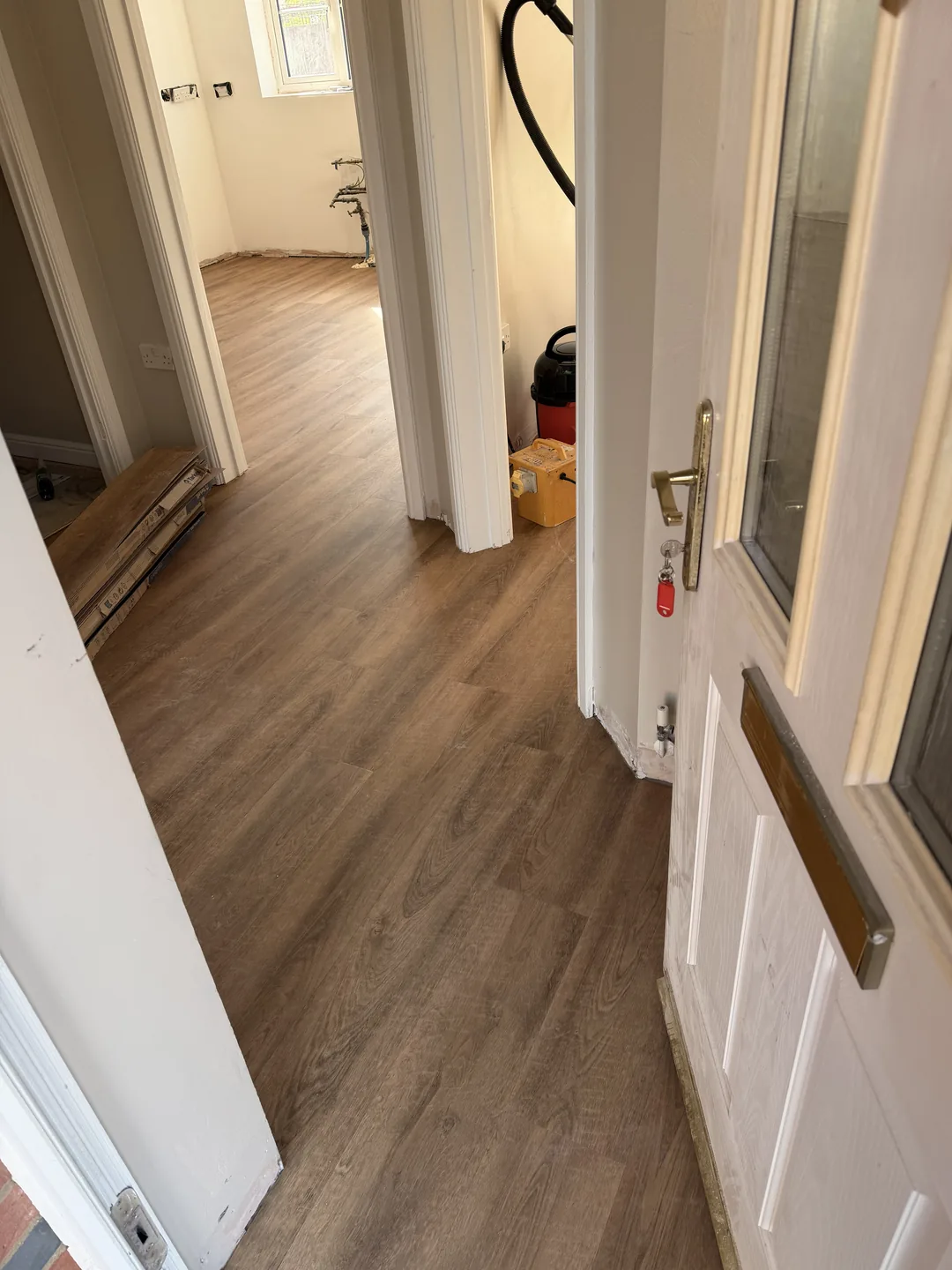 Wood-effect flooring laid through a hallway with packs of boards stacked nearby