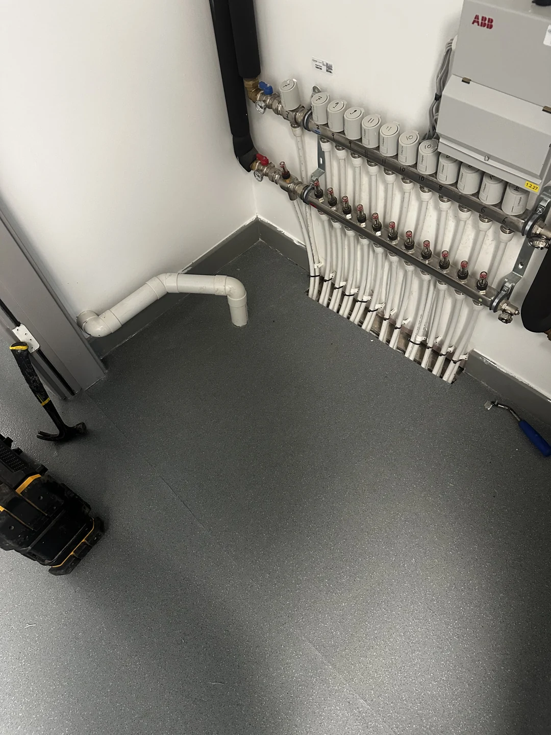 Grey service-room floor with fitted edges around pipes and equipment