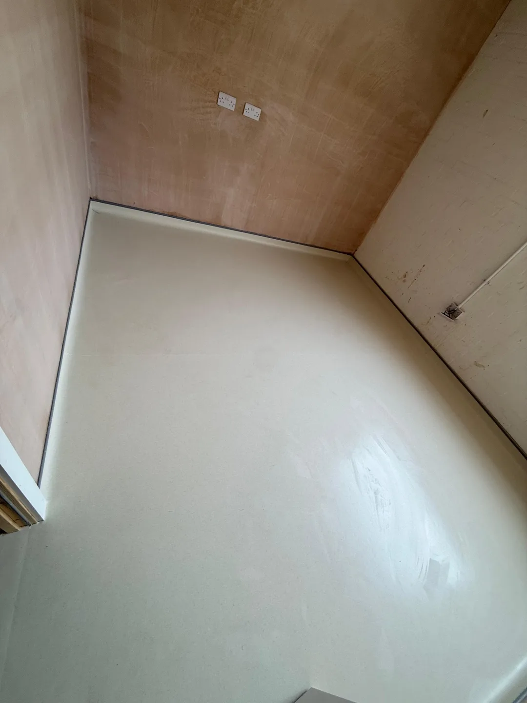 Smooth cream floor with coved edges in a room with plastered walls