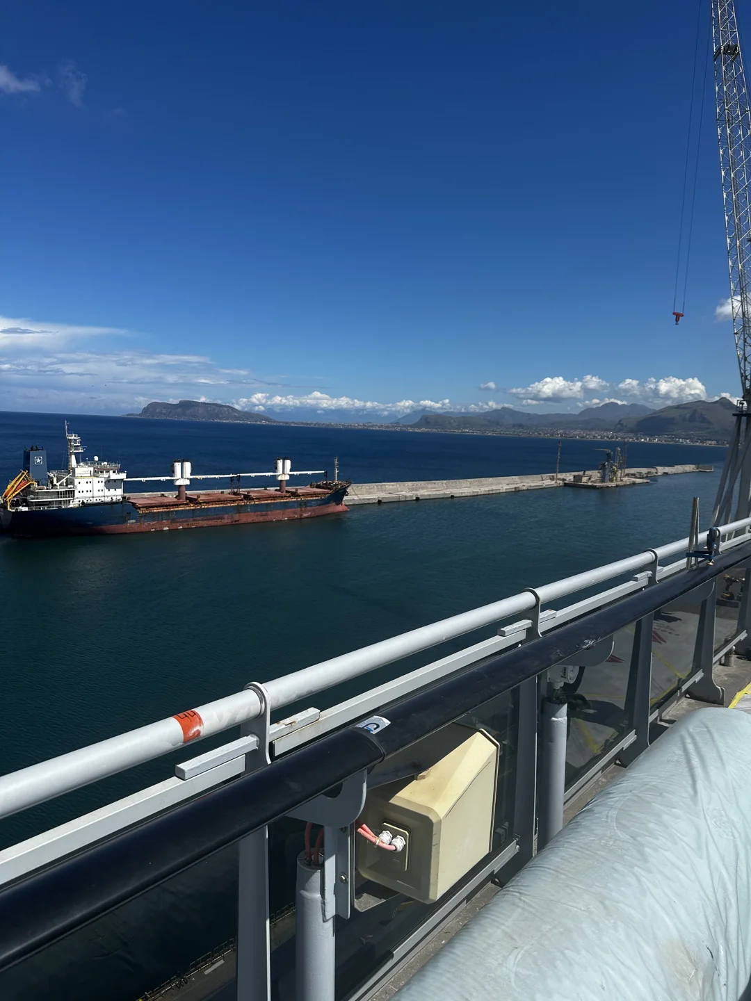 Waterfront and open water viewed over a ship-side railing