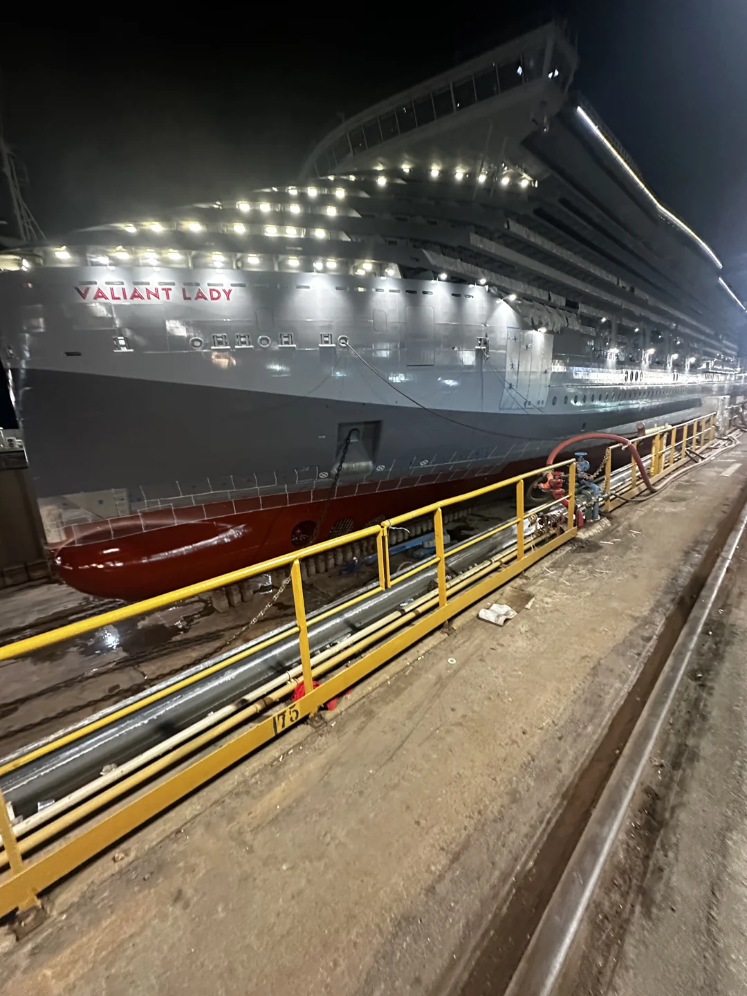 Illuminated ship beside a walkway and railing at night